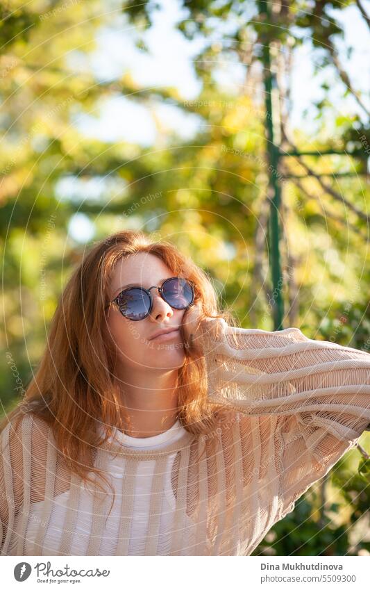 candid portrait of young beautiful woman in sunglasses. Pretty ginger girl with red hair. park smiling happy pretty Smiling cheerful attractive Woman Park