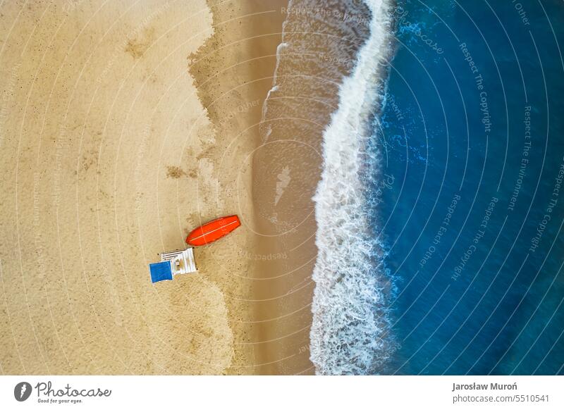 Aerial view of Baltic Sea shoreline with waves crushing sand beach during sunrise in the morning, lifeguard post and boat, drone photography no people