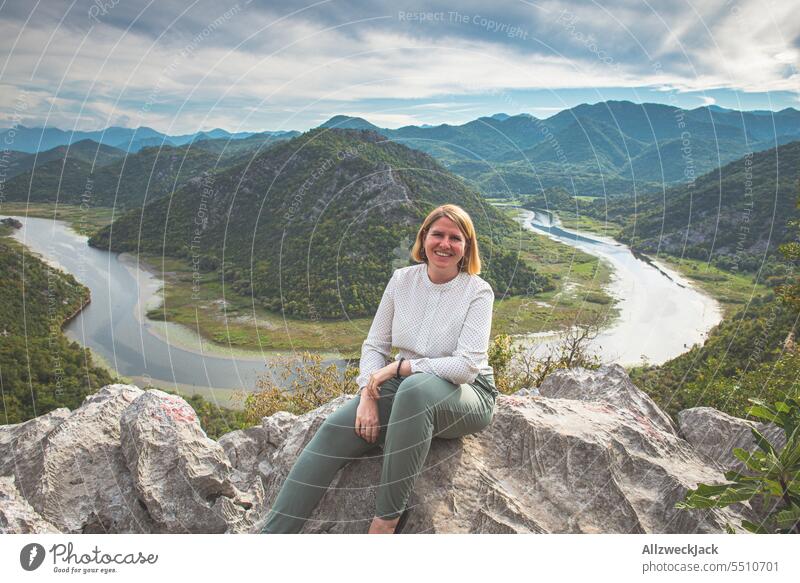 blonde middle aged woman sitting happily in front of beautiful panorama view with river Montenegro Panorama (View) Valley vantage point Vantage point