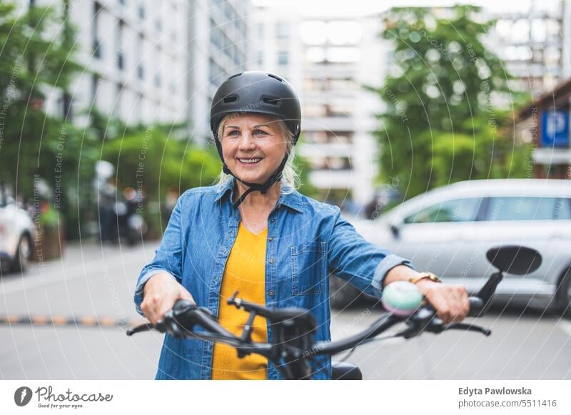 Portrait of senior woman wearing helmet while riding bicycle in the city people caucasian standing healthy city life gray hair enjoy street casual day portrait