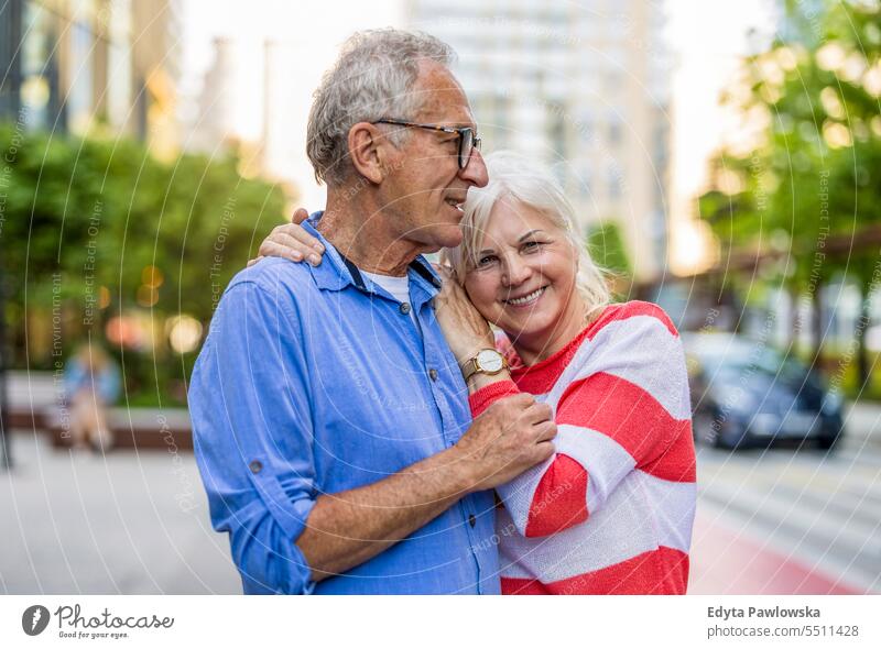 Portrait of a happy senior couple embracing in the city people caucasian standing healthy city life gray hair enjoy street casual day portrait outside