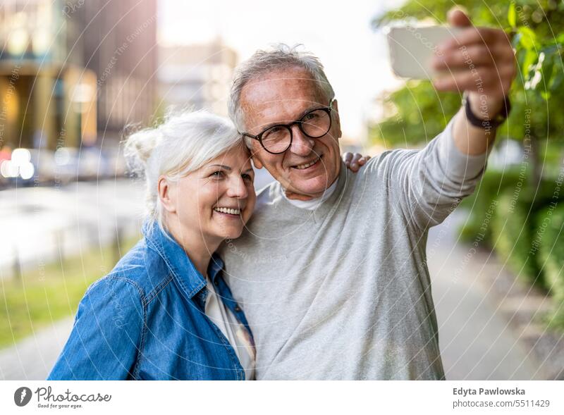 Senior couple using smartphone in the city people standing healthy city life gray hair enjoy street casual day portrait outside real people white people adult