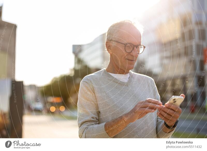 Senior man using smartphone in the city people caucasian standing healthy city life gray hair enjoy street casual day portrait outside real people white people
