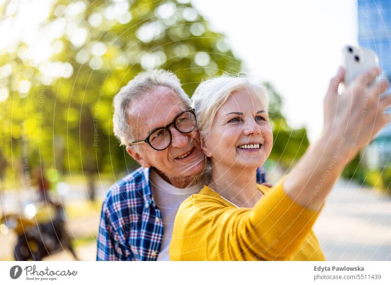 Senior couple using smartphone in the city people caucasian standing healthy city life gray hair enjoy street casual day portrait outside real people
