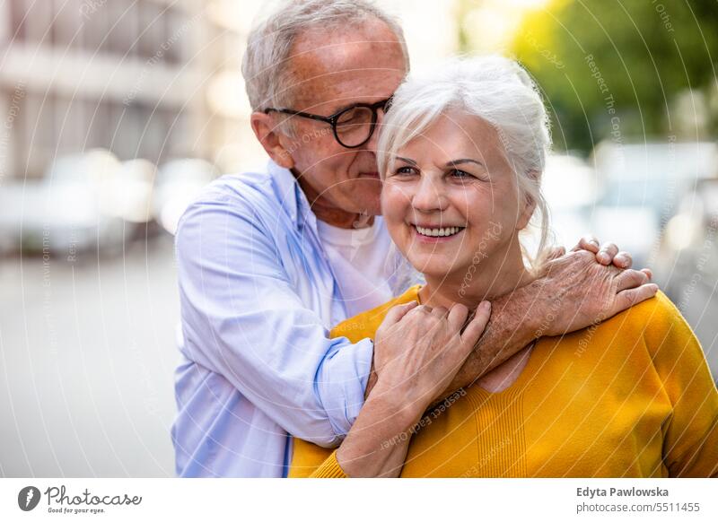 Portrait of a happy senior couple embracing in the city people caucasian standing healthy city life gray hair enjoy street casual day portrait outside