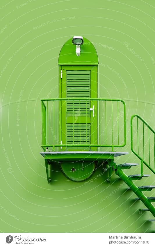Industrial metal door and stairs leading up a green painted windmill entrance industrial sunset energy industry staircase construction modern steel landscape