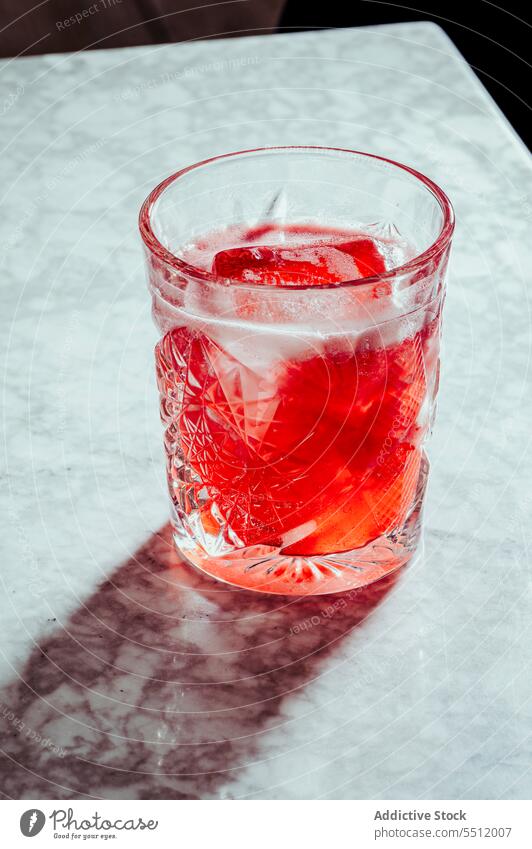 Glass of cold red alcohol drink cocktail glass refreshment ice cube beverage fizz liquid tonic marble bubble lemonade counter bar booze portion aperitif mix