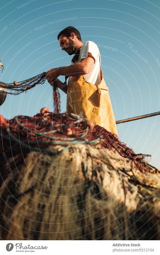 Man pulling net from sail boat in sea man fisher fishing untie trawler apron male fisherman soller balearic islands mallorca seine fish hunt schooner ship yacht