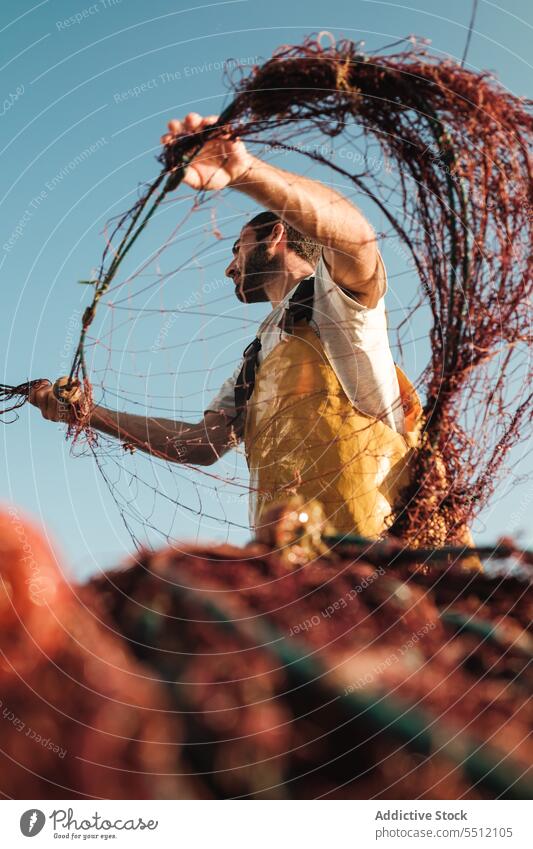 Man pulling net from sail boat in sea man fisher fishing untie trawler apron male fisherman soller balearic islands mallorca seine fish hunt schooner ship yacht