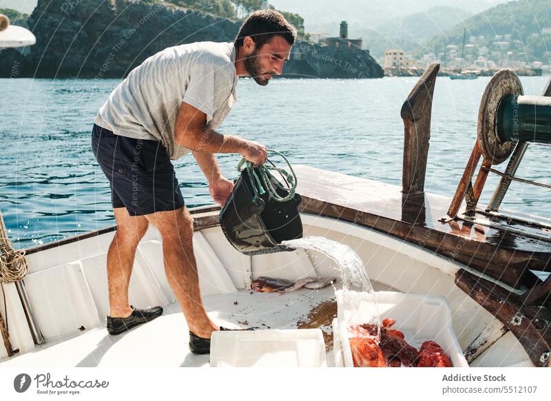 Hispanic man pouring water from bucket fishing boat fisher serious box male soller balearic island mallorca hispanic ethnic fisherman container nature transport