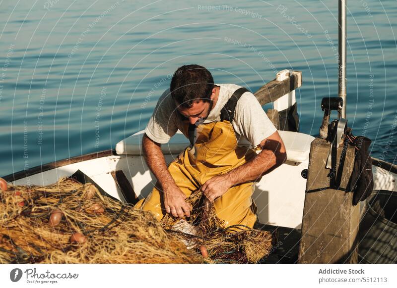 Fisherman untying net on sail boat in sea fisherman worker catch tradition fishing untie trawler male soller balearic islands mallorca sailor seaman seine fish