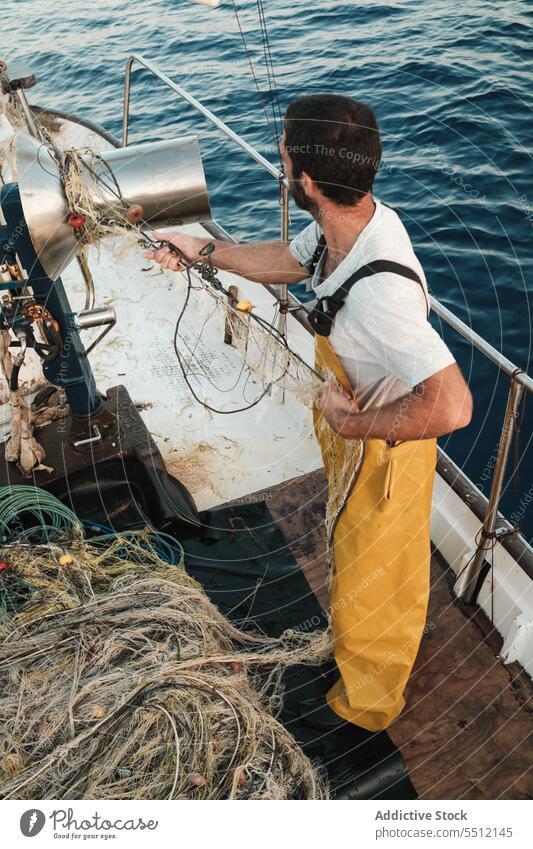 Fisherman fishing in open sea from sail boat fisherman net schooner work uniform focus male soller balearic islands mallorca seine fish hunt trawler