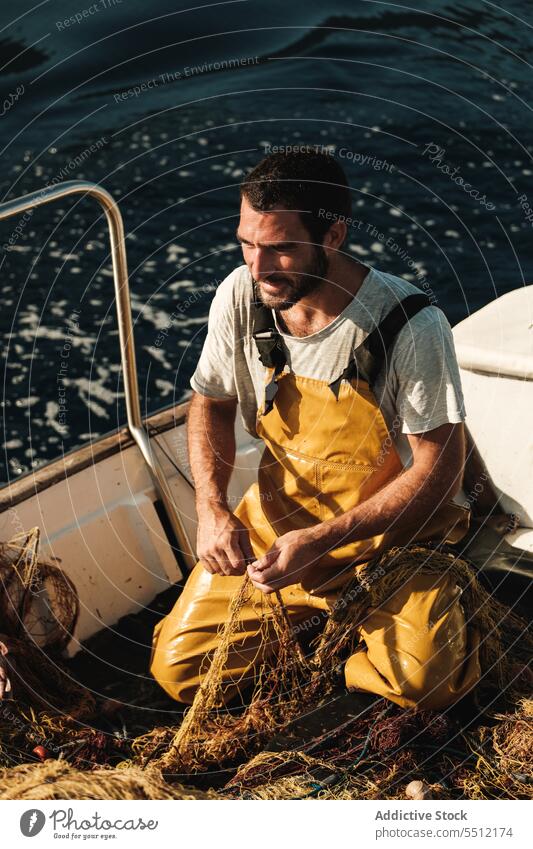 Fisherman untying net on sail boat in sea fisherman worker catch tradition fishing untie trawler male soller balearic islands mallorca sailor seaman seine fish