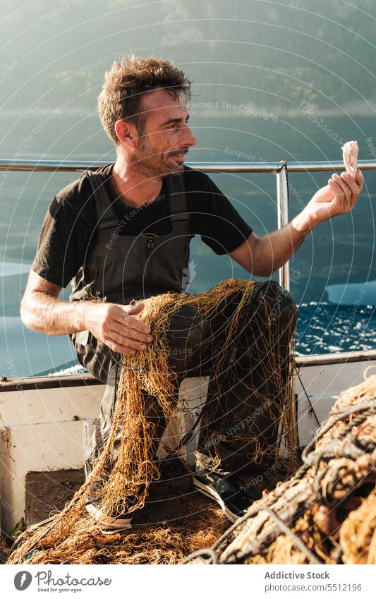 Seaman collecting caught sea food out of net on sea seaman fisher scallop seafood catch pick tradition fishing male soller balearic islands spain mallorca