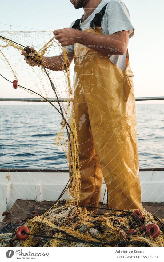 Hands of a man in camo pulling out a brown fishing net with small