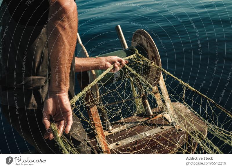 Anonymous fisherman fishing in open sea from sail boat net schooner work uniform focus male soller balearic islands mallorca seine fish hunt trawler