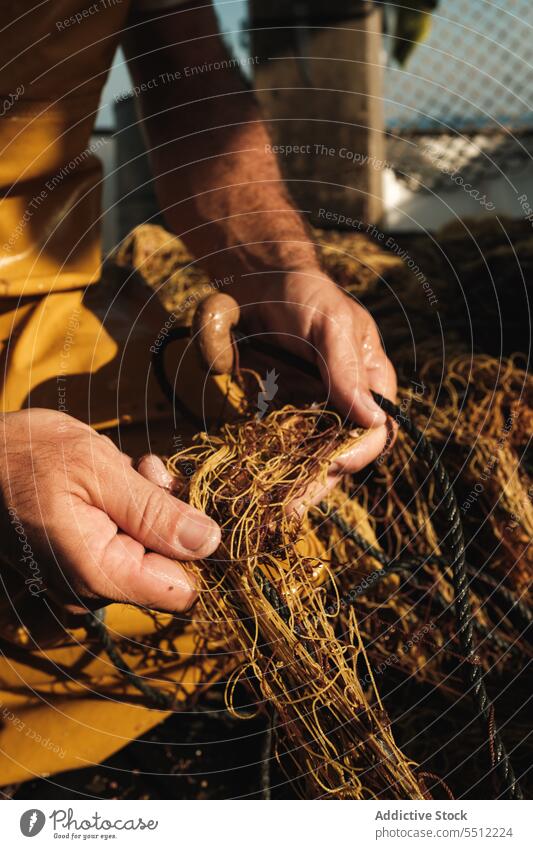 Anonymous man hand untangling fishing net threads to catch fish in daylight fisherman boat water deck equipment nature male transport outside wet aqua summer