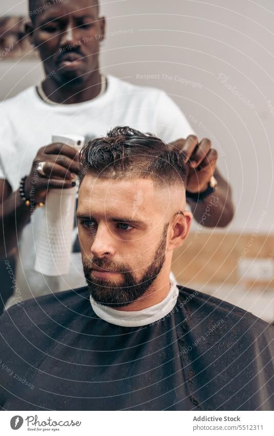 Black barber spraying water on hair of client men haircut salon barbershop sprayer masculine concentrate young male multiracial african american black wet hair
