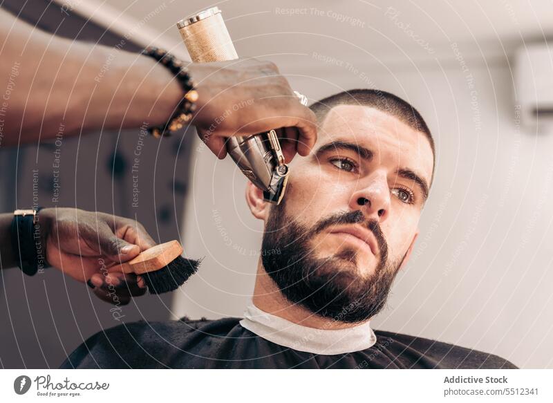 Professional barber shaving beard of client in barbershop men shave razor brutal beauty care young male multiracial black ethnic african american masculine