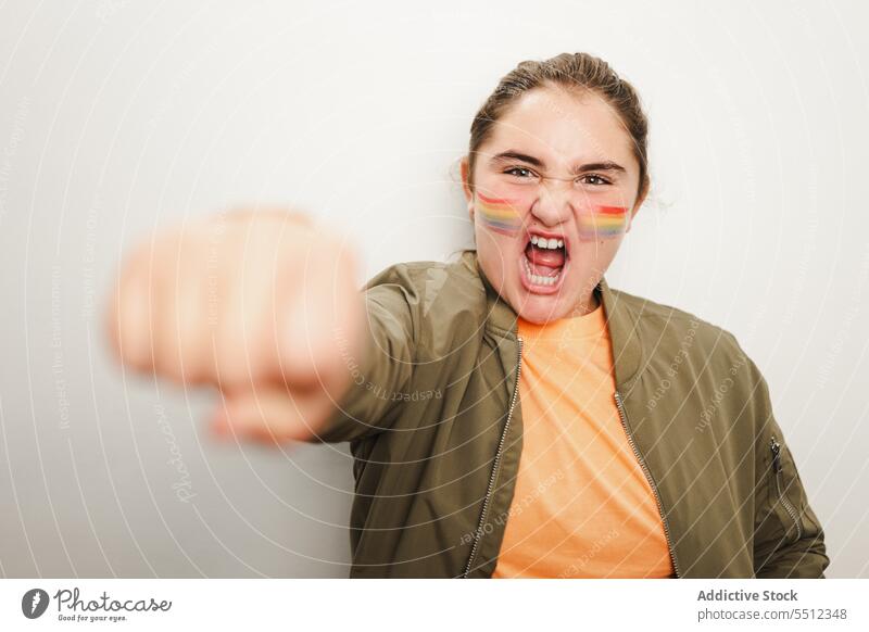 Serious young girl standing near gray wall with closed fist teenage lgbtq homosexual kid excited mouth opened fun joy playful positive aspiration energy triumph