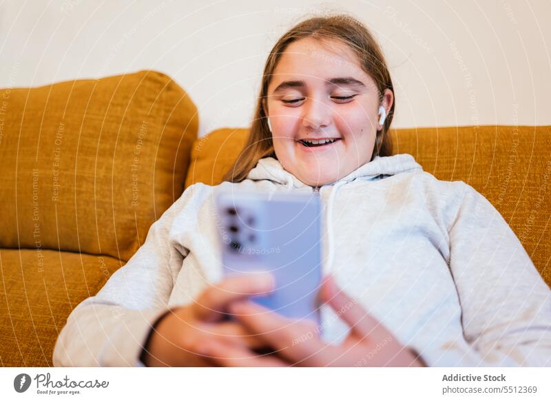 Cheerful young girl at smartphone while sitting on sofa video call smile online using communicate connection internet teen gadget device chat happy teenage