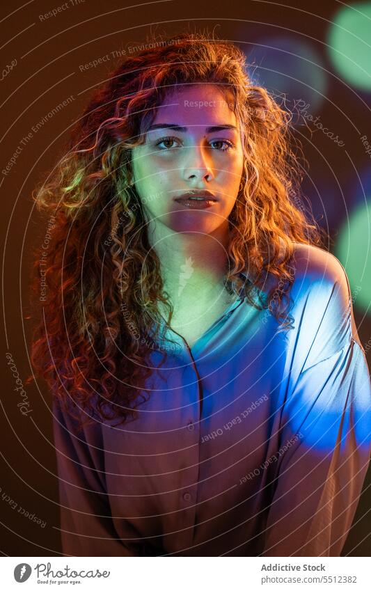 Attractive woman in room with neon lights portrait curly hair effect illuminate dot calm peaceful tranquil sensual young female lady long hair human face dark