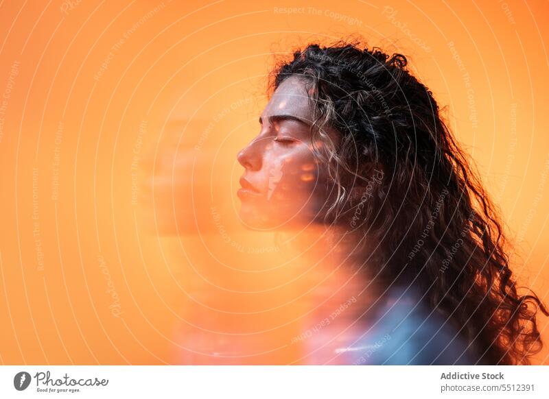 Calm curly haired woman with closed eyes effect illuminate neon dot calm sensual peaceful profile young female lady long hair brunette human face model light