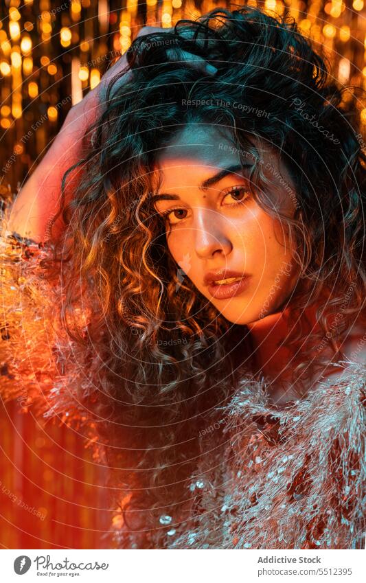 Attractive woman with curly hair in room with neon lights portrait touch hair adjust fix effect illuminate dot calm peaceful tranquil sensual young female lady