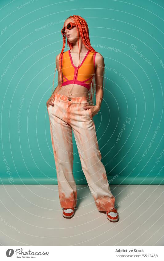 Stylish woman in orange outfit and sunglasses confident stylish fashion model studio shot unemotional cool vivid appearance young female afro braids top pants