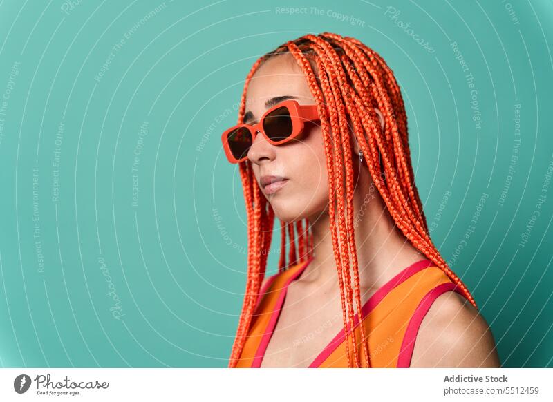 Stylish woman in orange outfit and sunglasses confident stylish fashion model portrait studio shot unemotional cool vivid appearance caucasian orange hair young