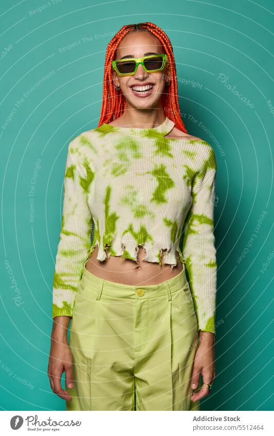 Stylish happy woman in green outfit and sunglasses confident stylish fashion model studio shot smile cool vivid cheerful appearance young female afro braids