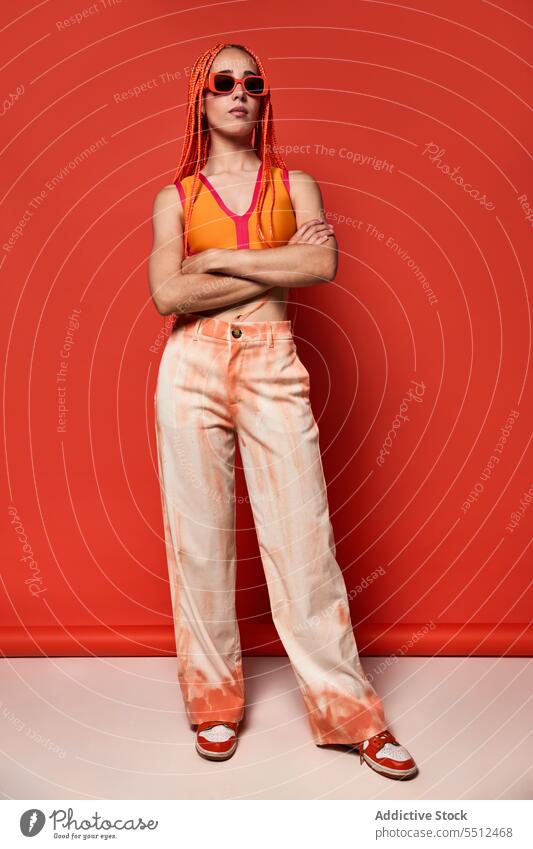 Stylish woman in orange outfit and sunglasses confident stylish fashion model studio shot unemotional cool vivid appearance young female afro braids top