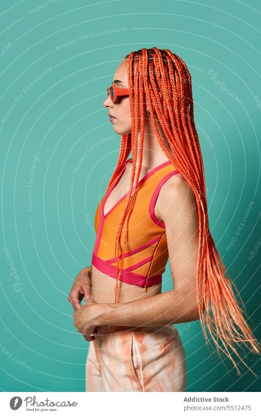 Stylish woman in orange outfit and sunglasses confident stylish fashion model portrait studio shot unemotional cool vivid appearance caucasian orange hair young