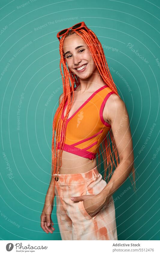 Stylish happy woman in orange outfit and sunglasses confident stylish fashion model studio shot smile cool vivid cheerful appearance young female afro braids