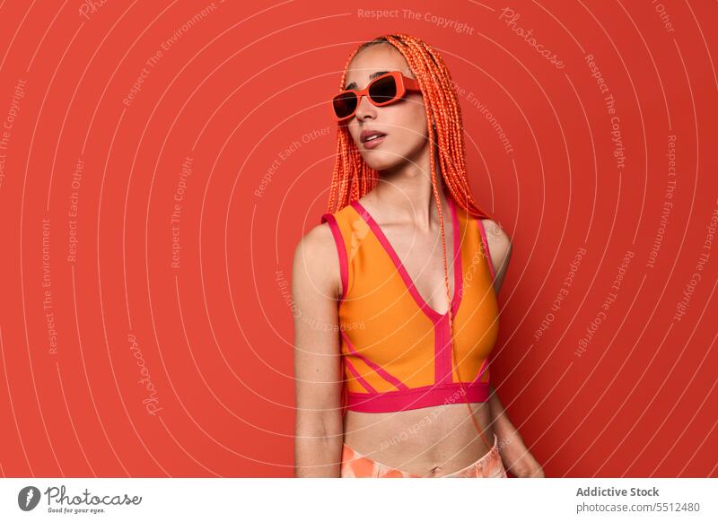 Stylish woman in orange outfit and sunglasses confident stylish fashion model studio shot unemotional cool vivid appearance young female afro braids top