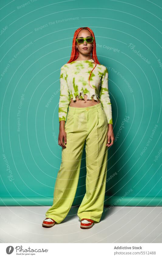 Stylish woman in green outfit and sunglasses confident stylish fashion model studio shot unemotional cool vivid appearance young female afro braids long sleeve