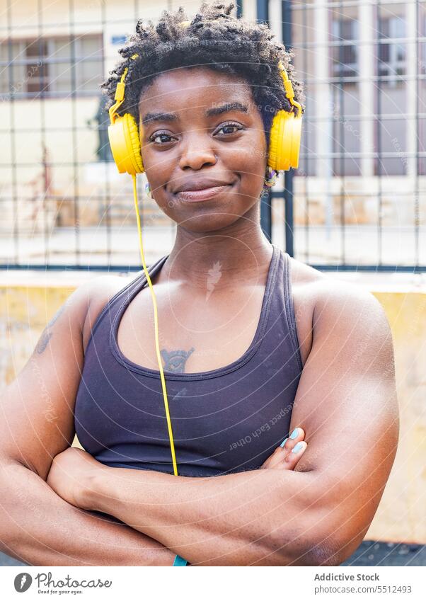 Satisfied African American female listening to music on street woman meloman headphones using melody audio dreamy enjoy sporty style ethnic lady