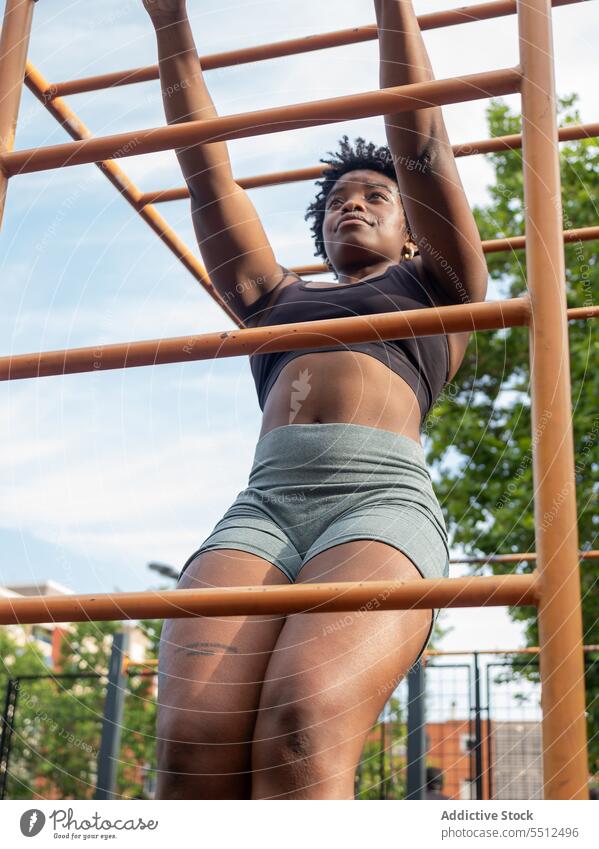 Focused strong young black woman doing exercise on metal bar in open gym sportswoman pull training workout muscular athlete female african american ethnic