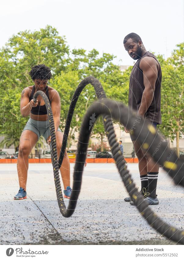 Black sportswoman doing exercise with battle ropes instructor trainer athlete determine training adult sportspeople functional black african american ethnic