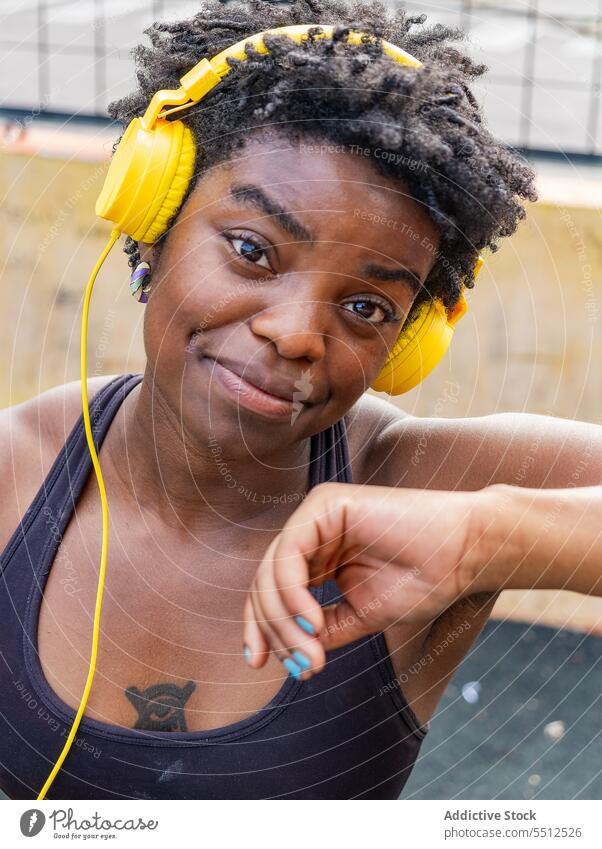 Satisfied African American female listening to music on street woman meloman headphones using melody audio dreamy enjoy sporty style portrait ethnic lady