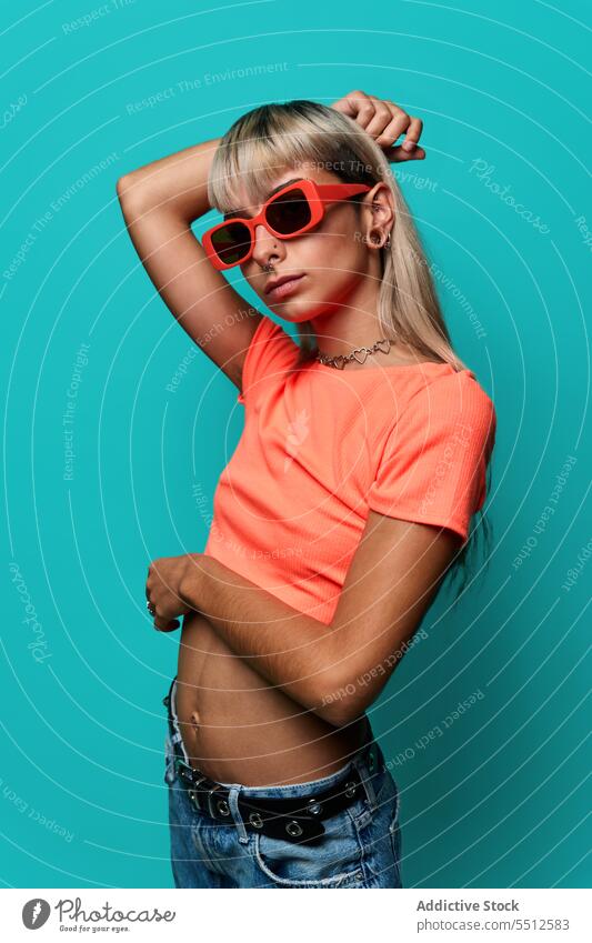 Confident trendy hipster woman in sunglasses hand on head street style posture studio shot informal subculture confident self confident self assured unemotional