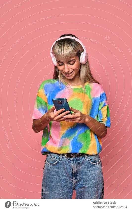 Young female hipster using smartphone in studio woman surfing internet headphones studio shot piercing message young blond smile trendy street style urban