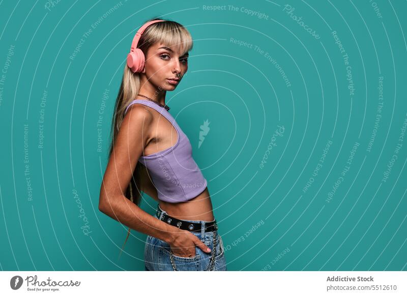 Young female listening to music in studio woman headphones song studio shot playlist free time meloman young blond casual style top jeans bangs model entertain