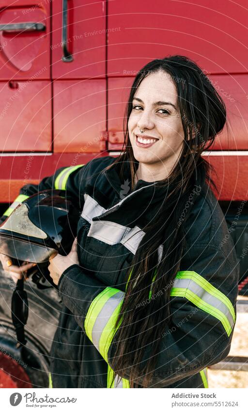 Happy female firefighter standing near fire truck woman uniform helmet occupation profession protect job smile positive happy young firewoman black hair pigtail