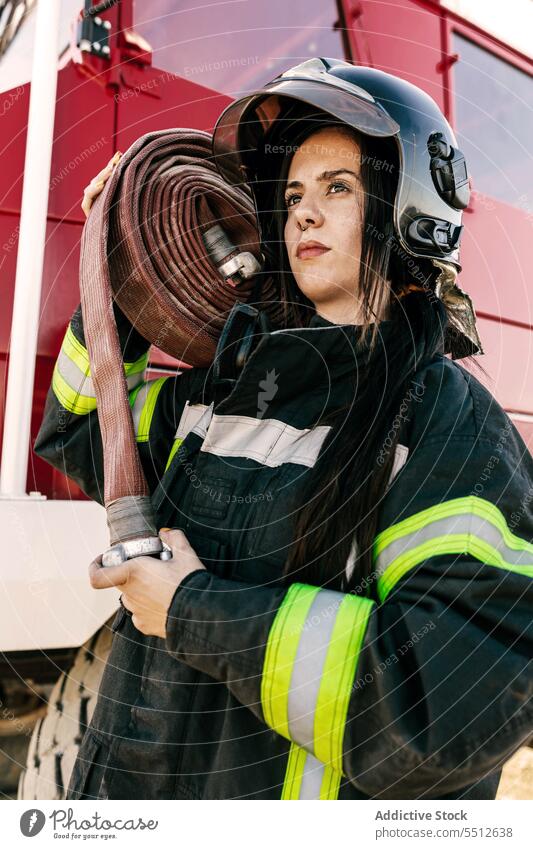 Young female firefighter carrying fire hose woman fire engine profession protect hero brave emergency young firewoman black hair safety professional daytime