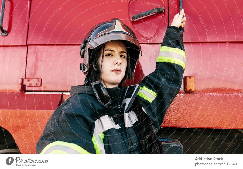 Brave female firefighter getting into fire truck woman prepare adjust helmet profession protect brave young firewoman black hair safety worker risk