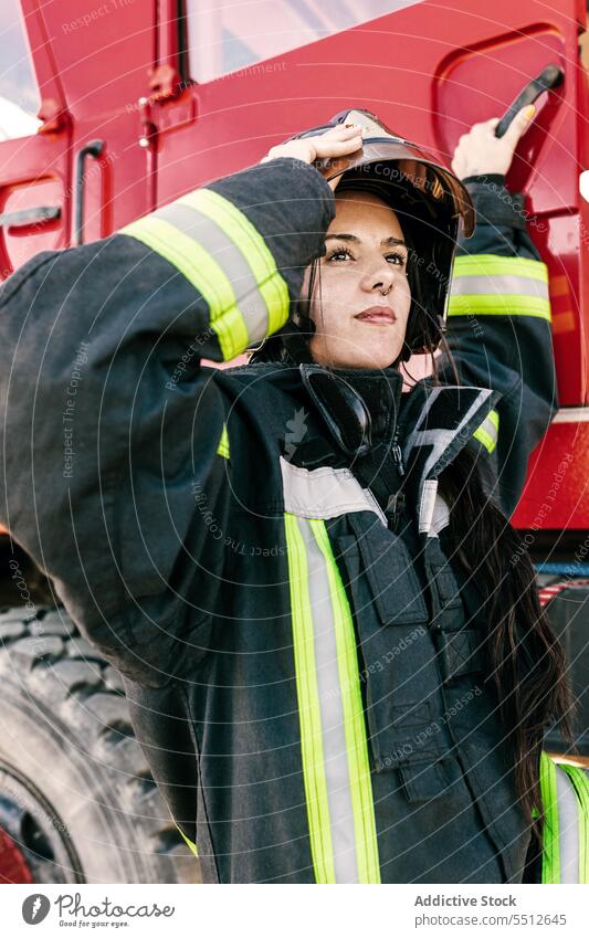 Brave female firefighter getting into fire truck woman prepare adjust helmet profession protect brave young firewoman black hair safety worker risk
