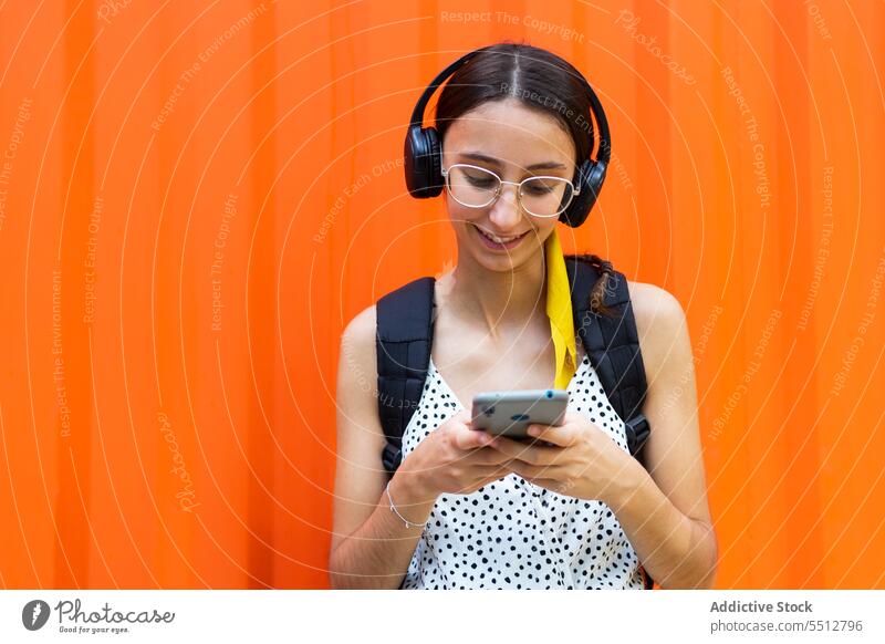 Cheerful woman using smartphone and listening to music headphones gadget happy cheerful browsing female mobile device young smile surfing cellphone sound