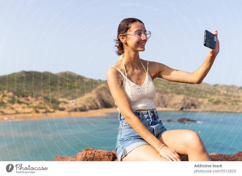 Happy woman taking selfie on smartphone sea happy summer water cheerful smile female mobile young device eyeglasses gadget photography positive optimist content