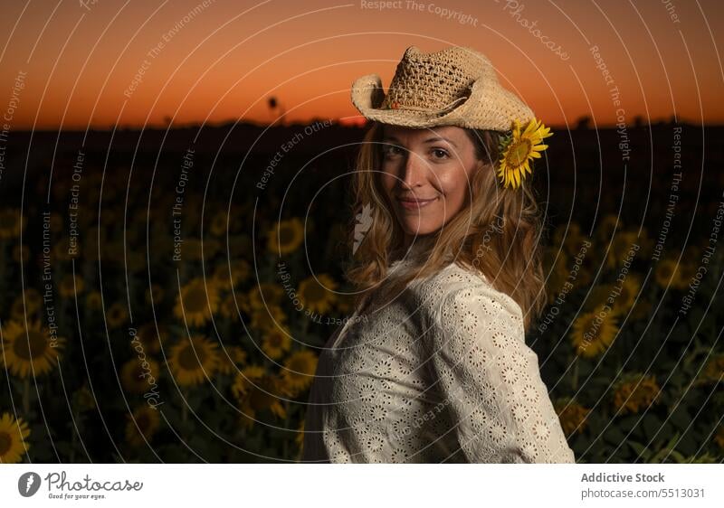 Smiling woman in straw hat standing in sunflower field positive countryside sunset summer enjoy rural nature female happy smile sundown environment content
